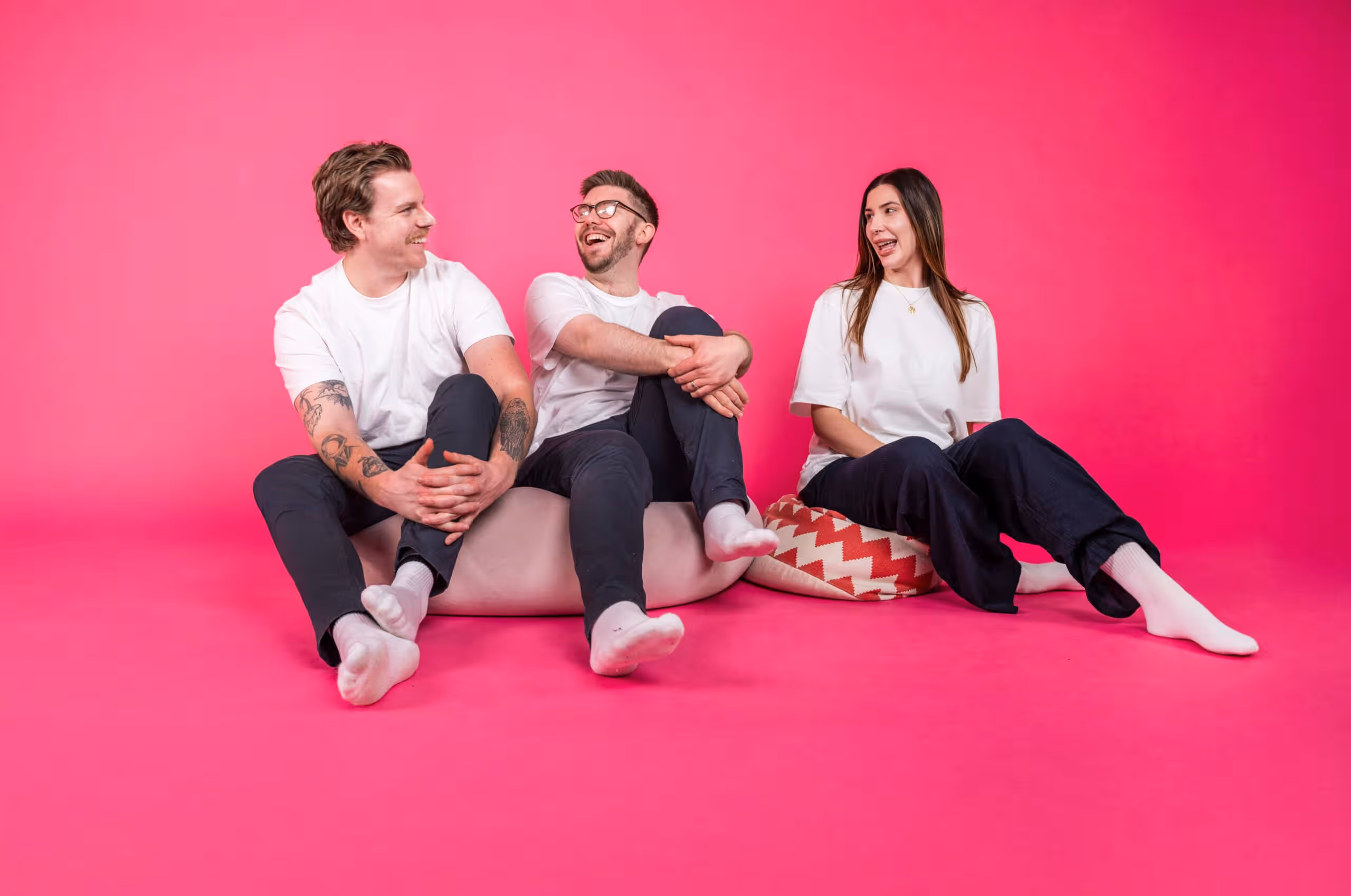 E-commerce marketing team of three against vibrant pink background
