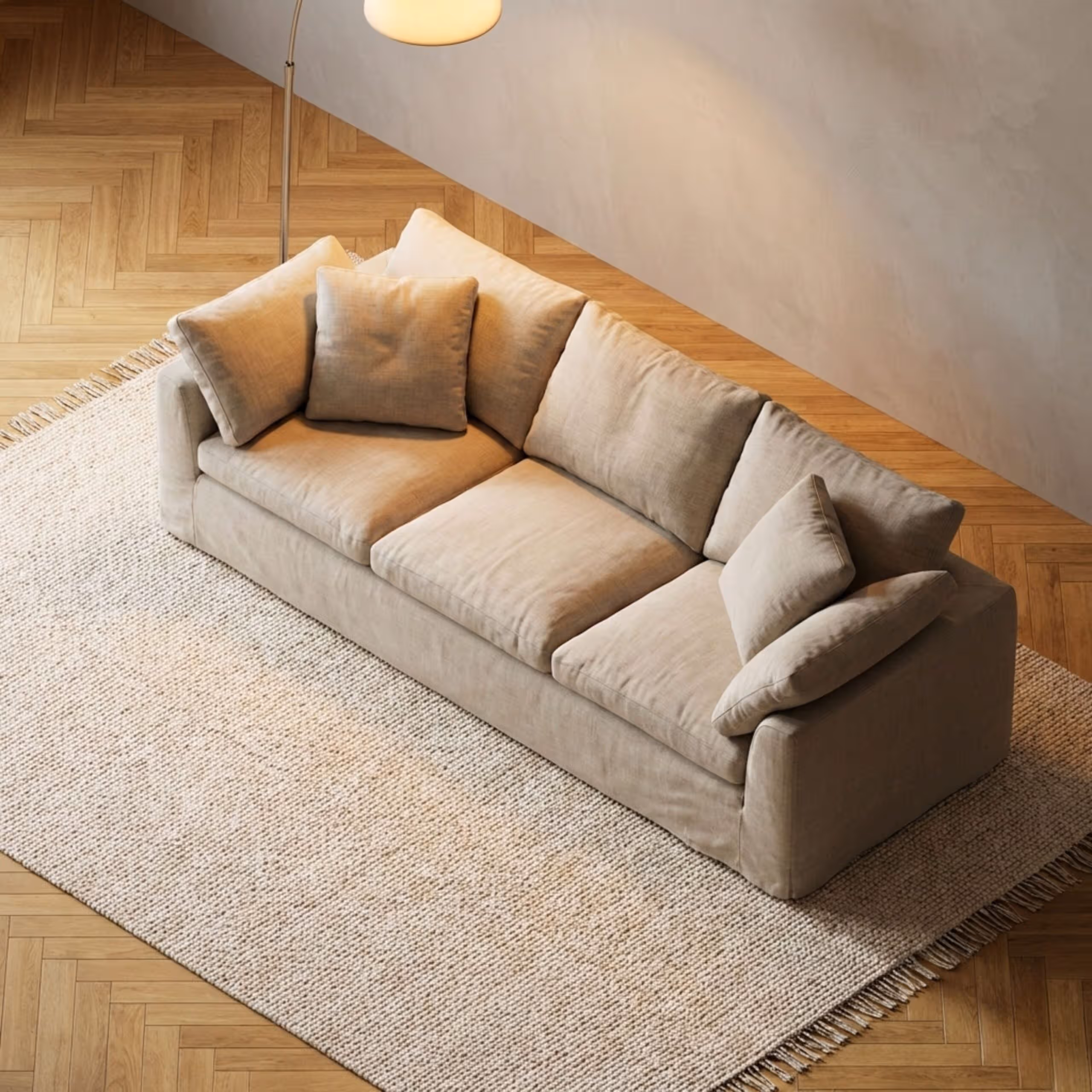 Beige sofa with cushions on a woven rug, wooden floor, modern living room ambiance.