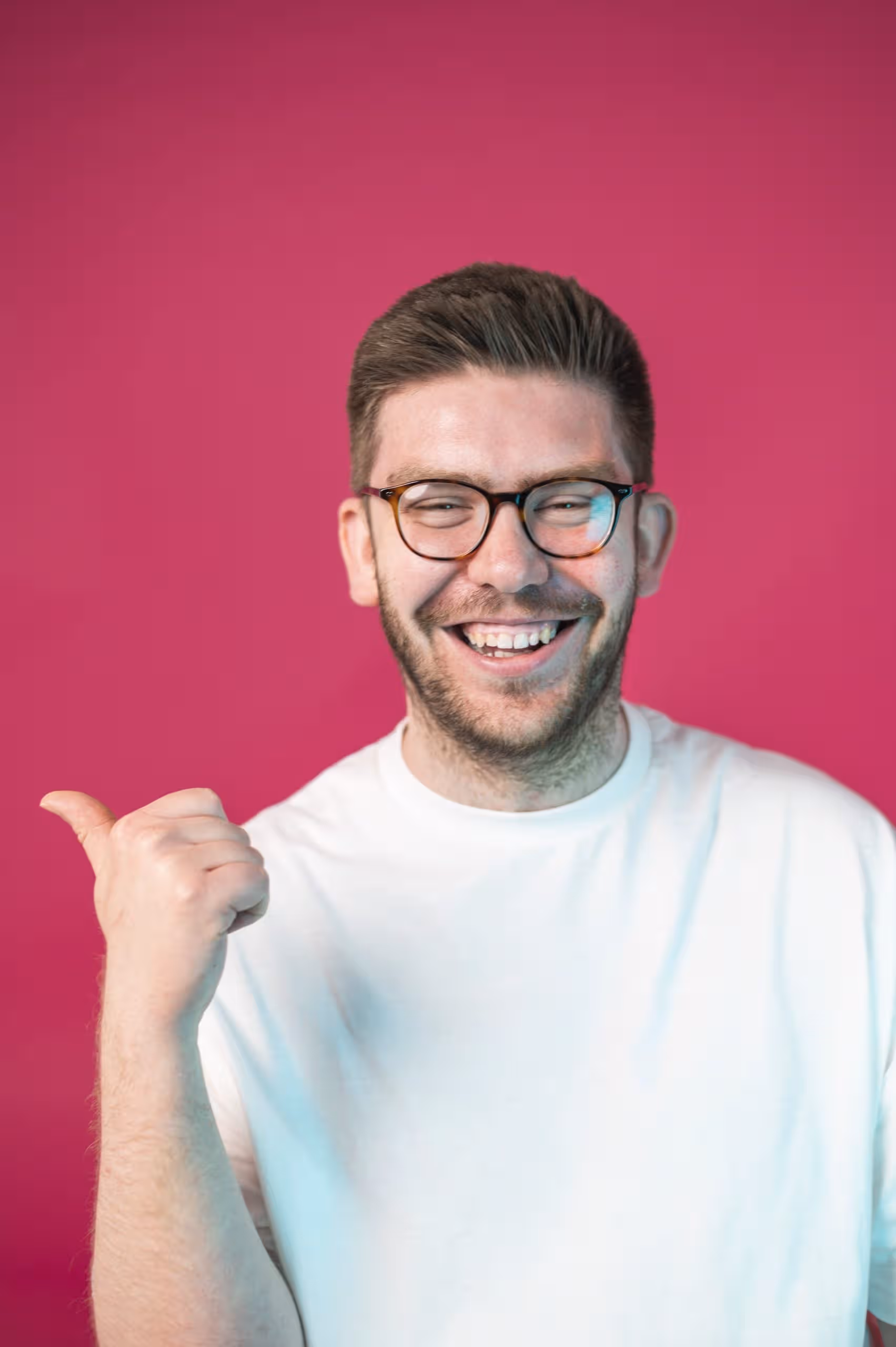 Smiling man in glasses gives thumbs up in front of pink background, symbolizing positive feedback at Salience marketing...